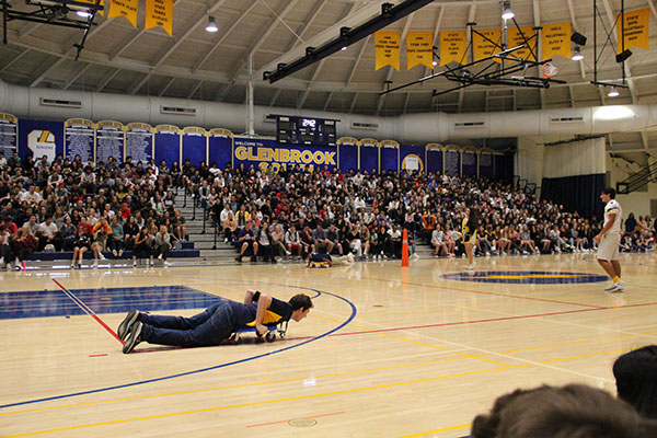 Boardin Boron: Scootering across the gym floor, Band Director Brian Boron participates in a Titan Nation competition during the 2019 fall sports assembly on Sept. 13. The sports assemblies were brought back as a tradition due to help from junior Grace Diehl’s Change.org petition. 