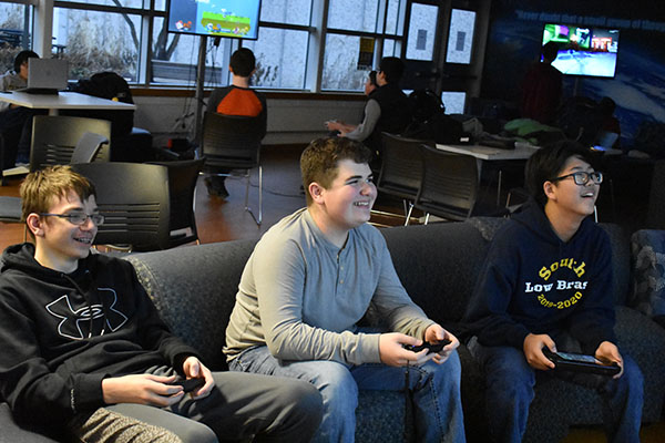 Grinning gamers: Jack Edgerly (left), Sean Minihane (middle), and Tim Walters (right) sit together in the SAC, enjoying their time at Gaming Club every Monday after school. Photo by Shoshana Green 