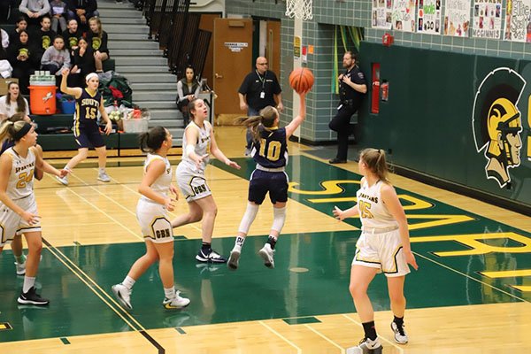 Rising Rogers: Dribbling up the court, sophomore Sidney Rogers, girls’ basketball player, analyzes the defense at a basketball camp and finishing around the rim, Rogers goes up in traffic against Glenbrook North last year. Though she has only been at South for one full year, her impact on the varsity girls’ basketball team has already been prevalent.