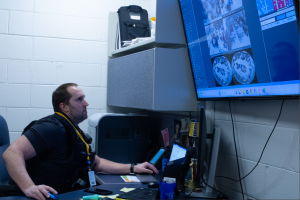 Under Watch: Officer Adam Uscicki keeps surveillance at South from his office, with monitors projecting live feedback from the building’s 177 security cameras, inside and outside the school. The camera’s footage can be used in cases of car accident outside, altercations inside, and stolen property. Photo by Gaby Yap 
