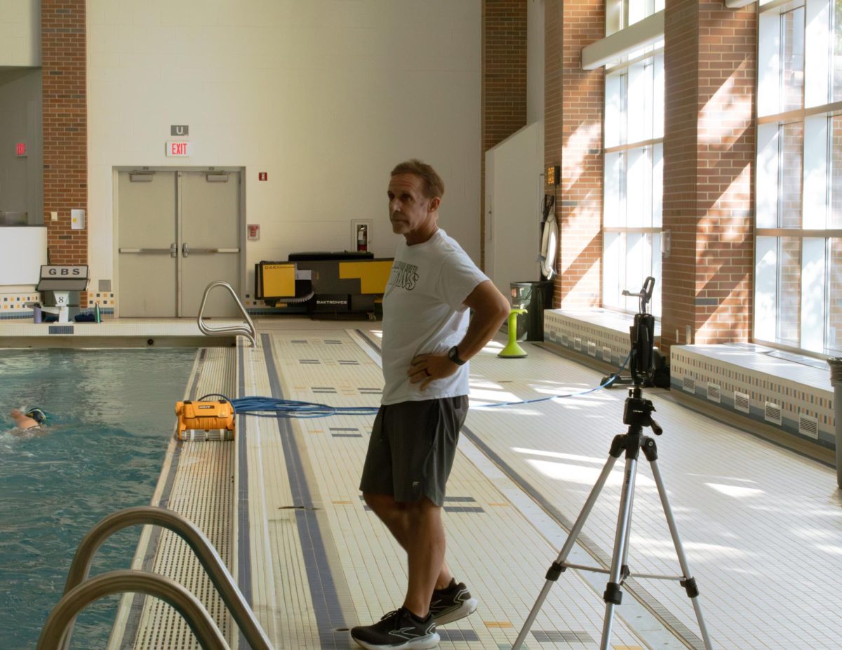 DYNAMIC  DIVING: Coach Mike Schulewitz is seen critiquing and instructing varsity freshman diver, Alexis Tsou. By visualizing and rewatching dives, Schulewitz helps his divers improve their skills with constructive criticism. 					                              Photo by Anne Sullivan Beltran