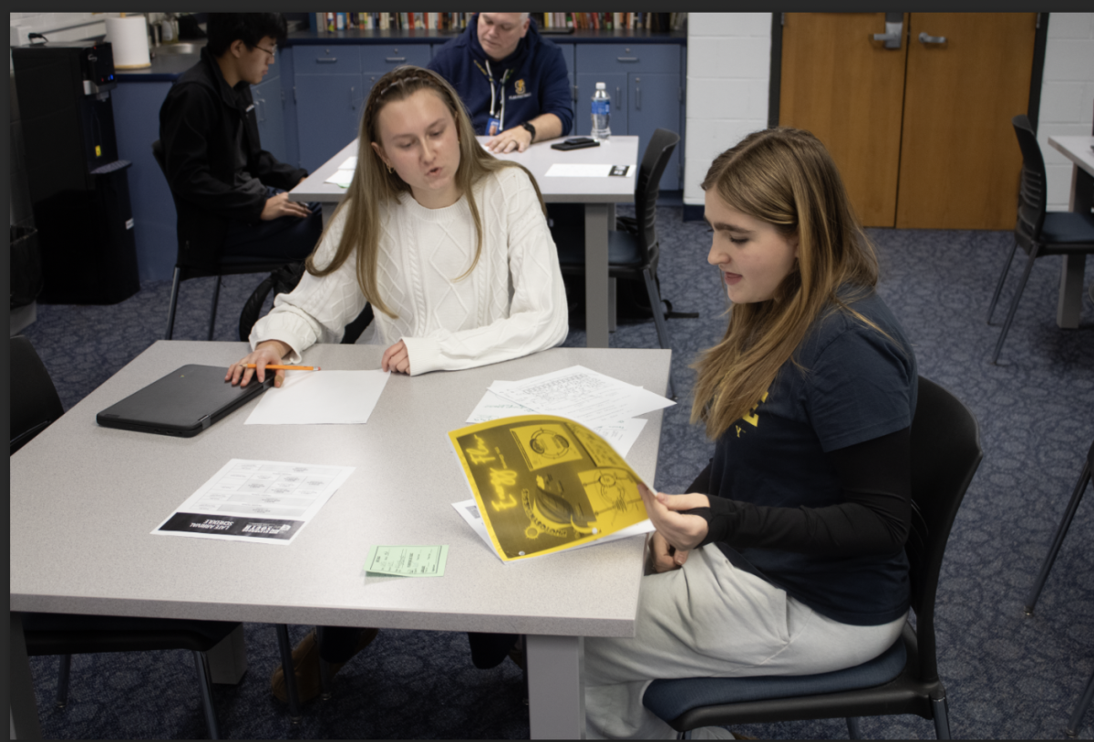 BONDING OVER BIOLOGY: Senior Reese Dahlberg, Titan Learning Center (TLC) tutor (left), and freshman tutee Olivia Brisch (right) unpack a study packet for Brisch’s biology class in the TLC. Dahlberg passes along study tips in hopes of making the stressful science final easier. 
