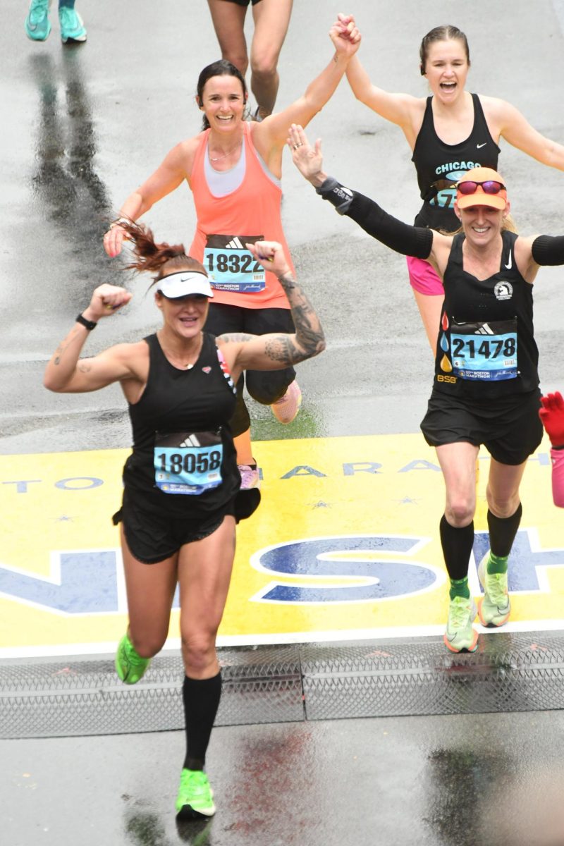 Meaghan Fastert (back left) holds
hands with Spanish Teacher Natalie Sells (back right). They near the finish line at the Boston Marathon in 2022.