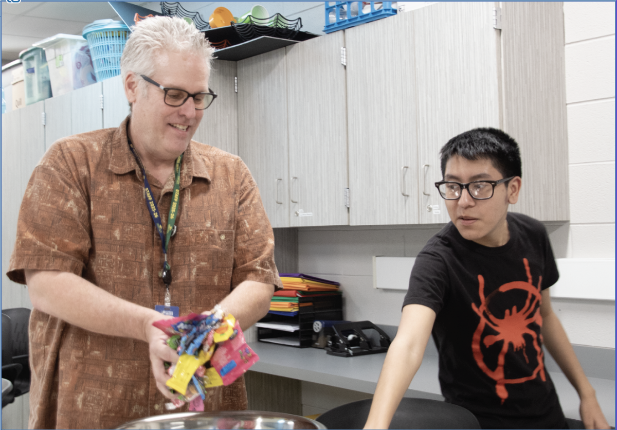 ANIME ACTION: Joe Mulloy, Special Education Job Coach (left), prepares snacks for a movie with senior Alfonso Hernandez (right) in Anime Club. Anime Club meets every Thursday in Room 2329. 