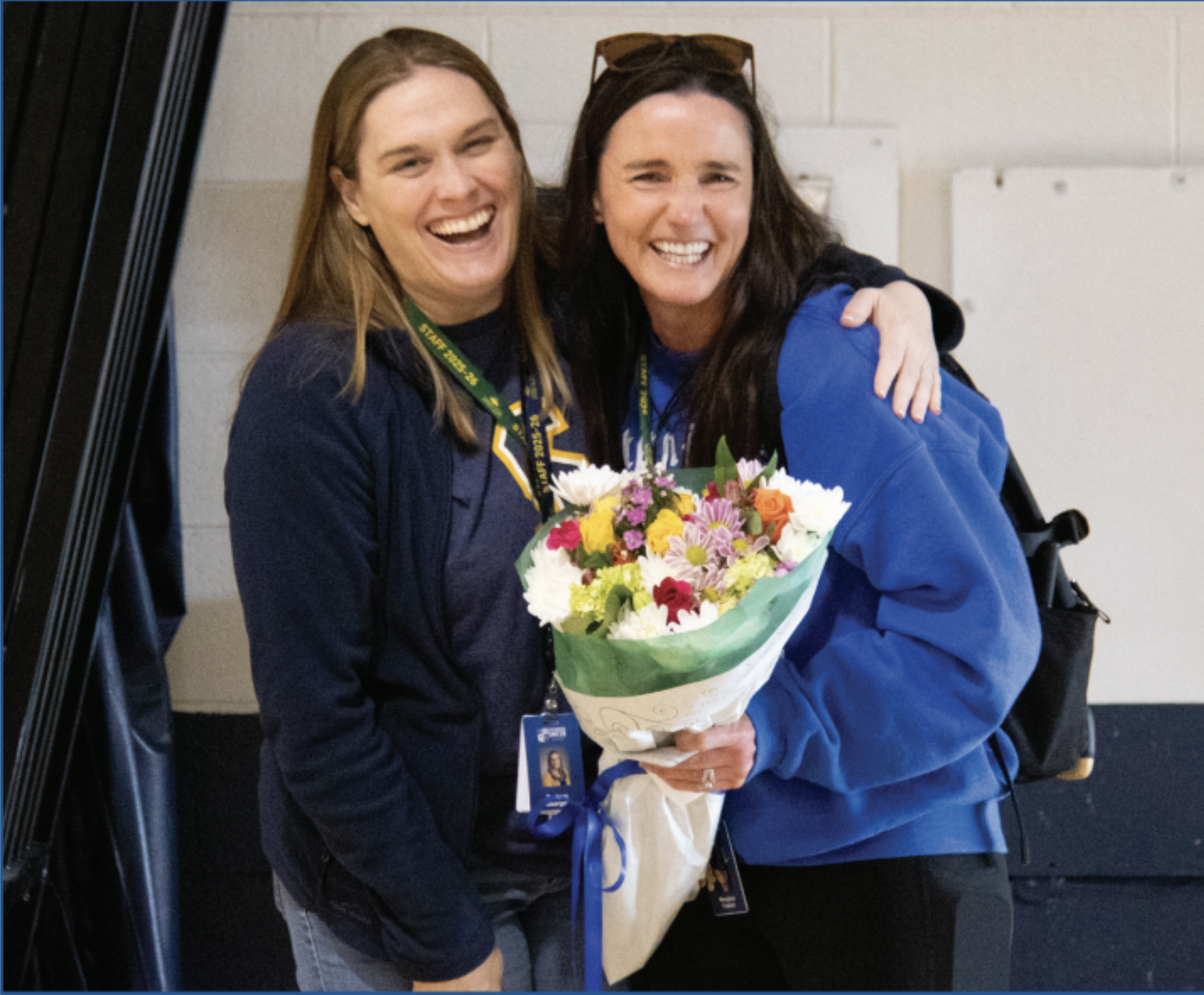 LEADING BY EXAMPLE: Principal Dr. Barbara Georges (left) surprises Meaghan Fastert (right), P.E. Teacher and Distinguished Teacher of the Year, with a bouquet of flowers to signify her achievement. After receiving the flowers, Fastert was met with balloons and desserts delivered by Joshua Stanton, P.E. Instructional Supervisor.