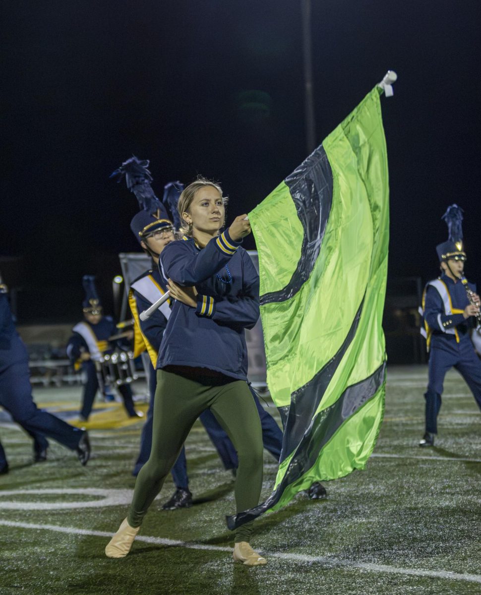 COLOR CREATION: Senior Keira Stender flips her flag in the air, creating visual effects supporting the music at the homecoming football game. Stender wows the crowd with her impressive dance moves and performance, creating an engaging show. 