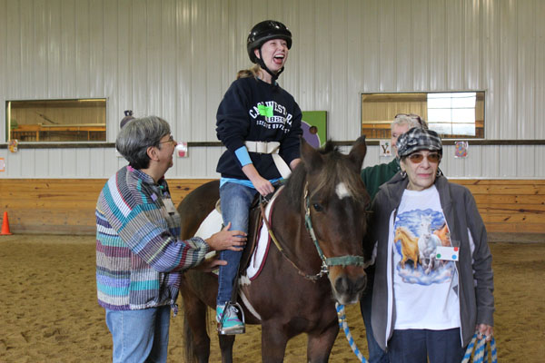 HORSIN AROUND: Smiling big, junior Hannah Flanagan jokes around as she rides a horse at Equestrian Connection, a therapeutic horse stable in Lakeforest, Illinois. Equestrian Connection is one of the many events that Circle of Friends club has participated in this year.